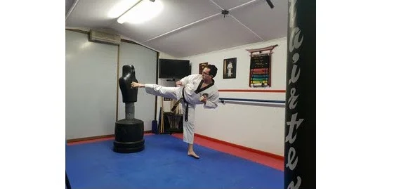 Martial artist performing a front foot side kick in a dojo.