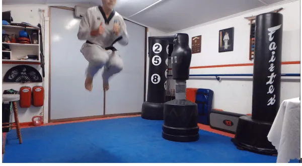 Martial arts instructor performing a jump exercise in a dojo.