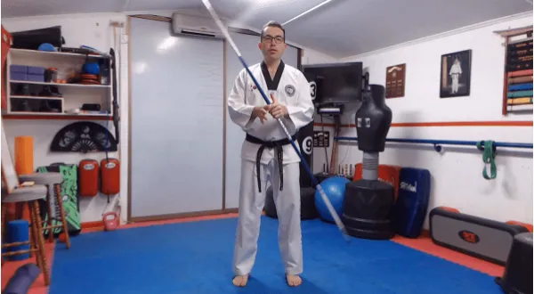 Martial arts instructor holding a bo staff in a dojo.