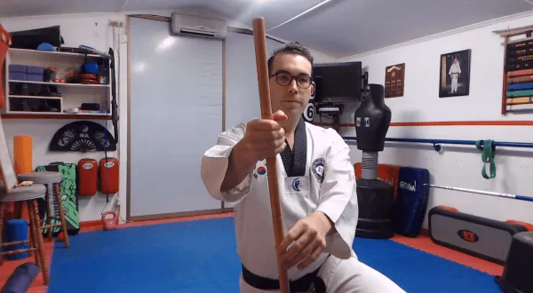 Martial arts instructor holding a bo staff in a defensive stance.