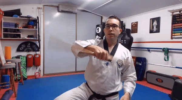 Martial arts instructor demonstrating a bo staff movement in a dojo.
