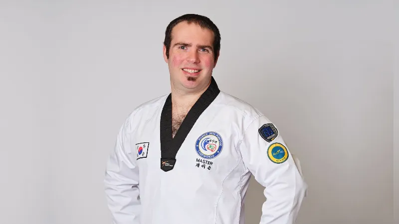 Man wearing ang black belt smiling at the camera