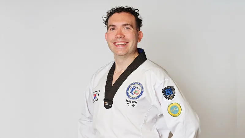 Man wearing a black belt smiling at the camera