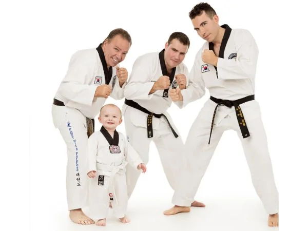 Three black belter men with a baby wearing Gi