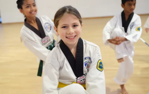 Young Taekwondo students smiling and practising martial arts techniques during class.